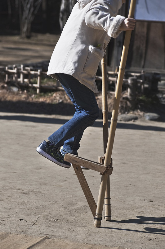 A by playing with a takeuma or Japanese stilts.